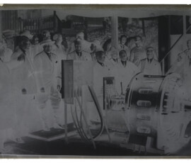 Guido Ucelli e Benito Mussolini, insieme a un gruppo di persone, osservano il motore elettrico di una pompa