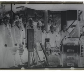 Guido Ucelli e Benito Mussolini, insieme a un gruppo di persone, osservano il motore elettrico di una pompa